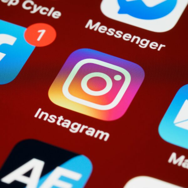 Close-up of a mobile phone screen showing various app icons, including Instagram, Facebook with a notification badge, Messenger, and a mail app. The Instagram app is in focus.